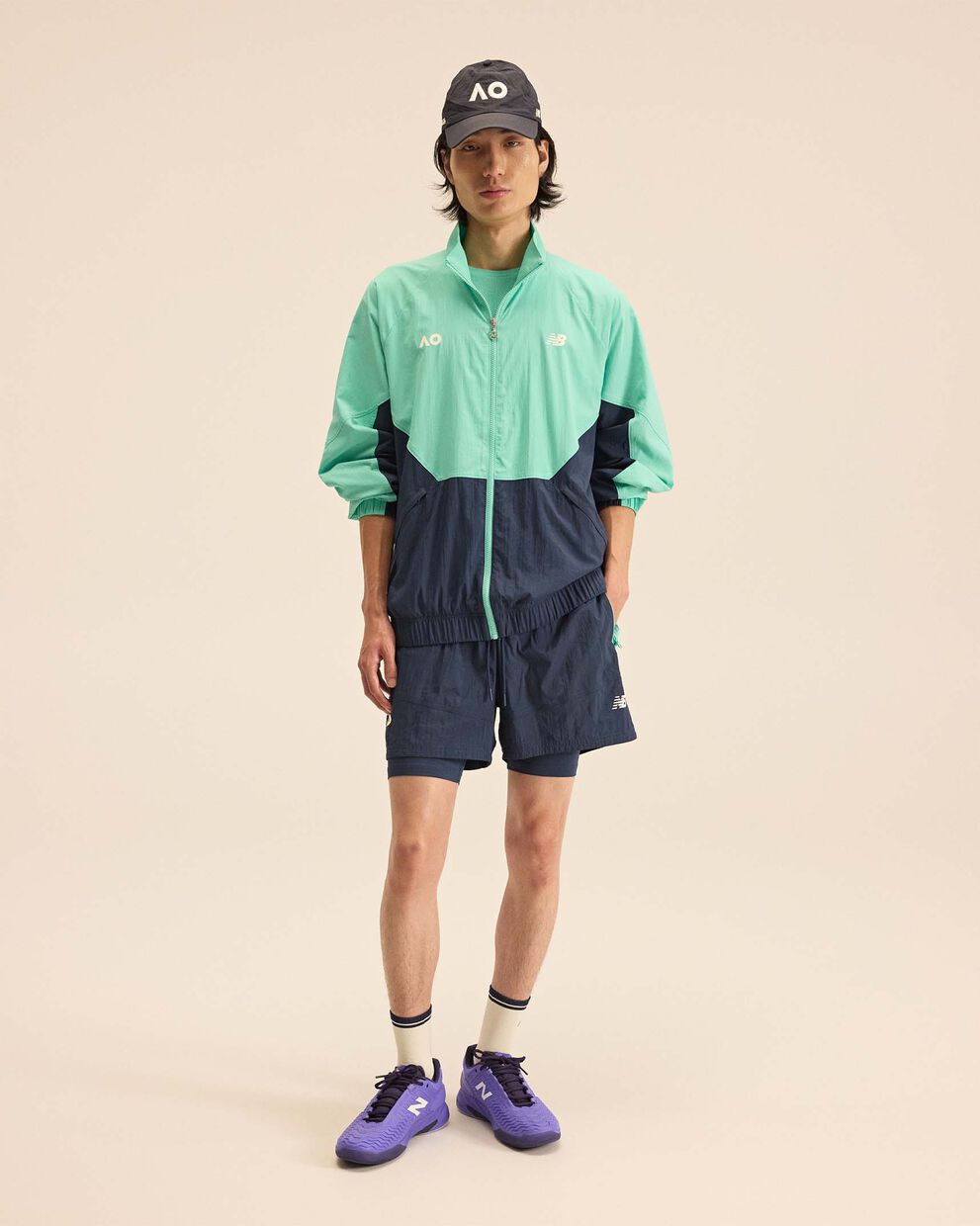 A person standing against a tan studio backdrop.