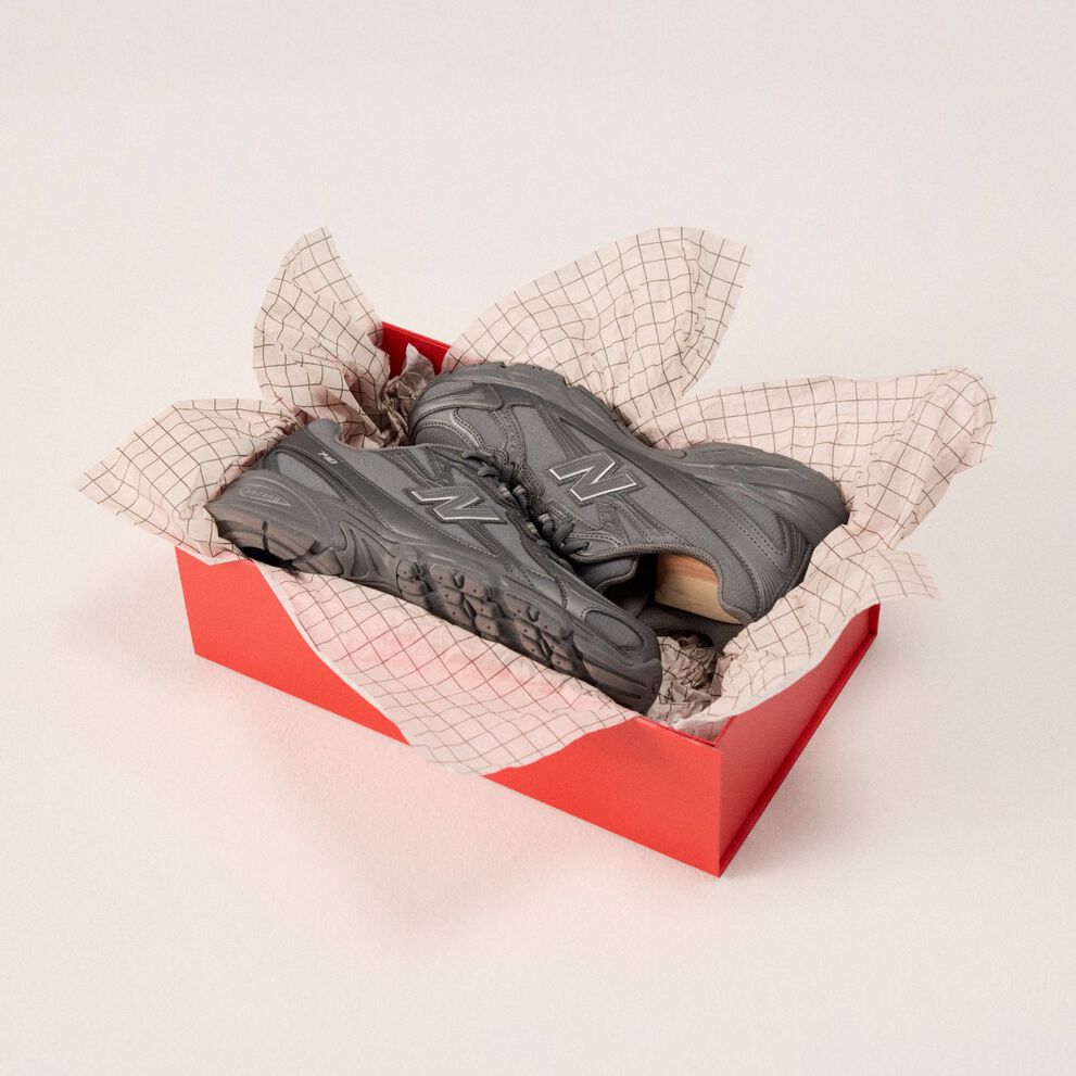 Pair of grey shoes in a box with wrapping paper.