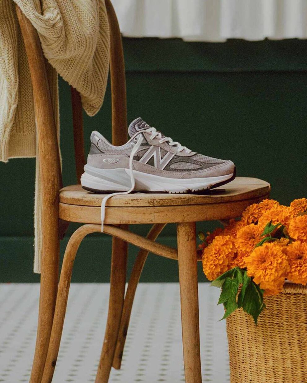 A grey 990v6 sneaker sitting on a chair in a cafe environment. 
