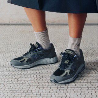 A pair of New Balance Made in UK sneakers sitting on a concrete floor.