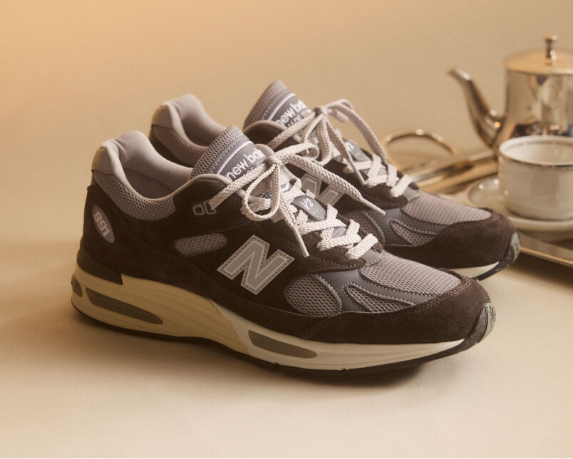 A pair of New Balance Made in UK sneakers in front of a rabbit in a brown textured studio environment. 